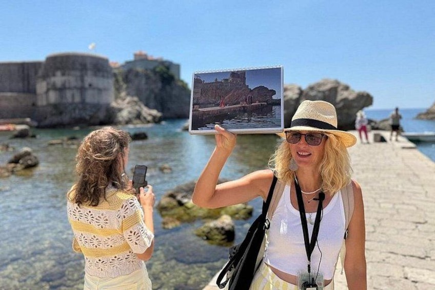 Two people taking a photo of a coastal area with clear water and rocky formations. 2