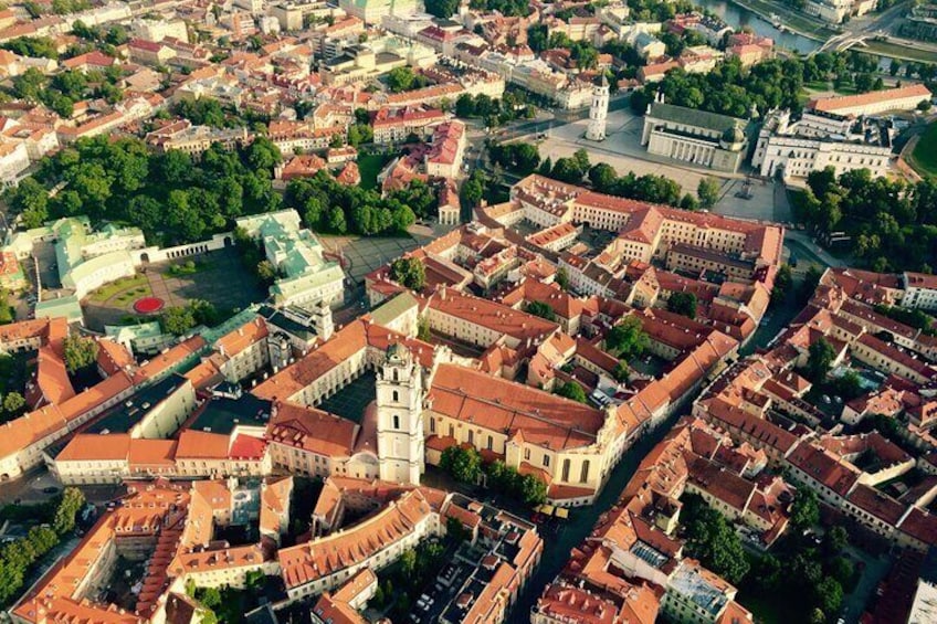 An aerial view of a historic city center with prominent buildings, a central square, and a river. 1