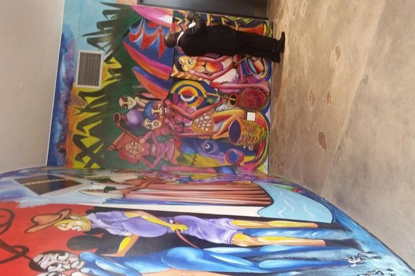 Un murale colorato su una parete, un letto con un disegno di un personaggio dei cartoni animati e una giacca nera appesa al muro. 3