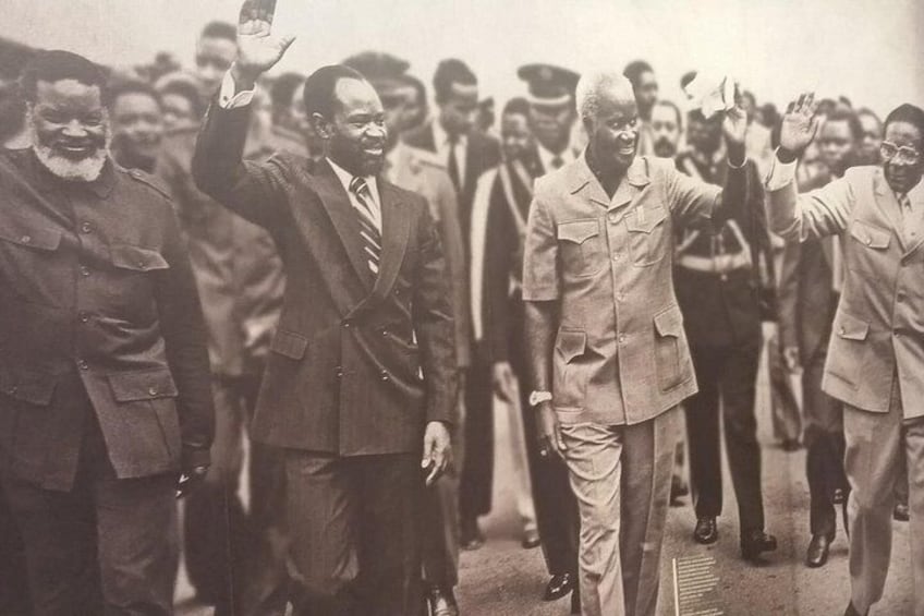 A group of men in suits walking together, some waving. 2