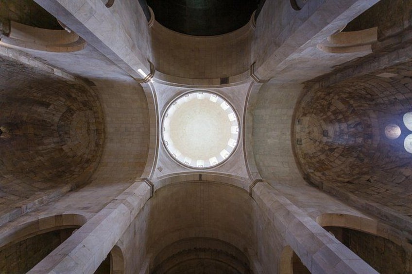Une lucarne circulaire dans un plafond en pierre, soutenue par quatre colonnes. 4