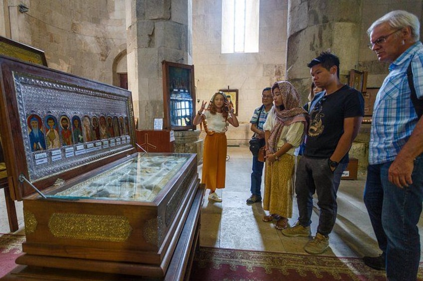 Un groupe de personnes se trouve à l’intérieur d’une église, observant une vitrine contenant des icônes religieuses. 3