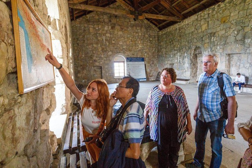 Un groupe de personnes se trouve à l’intérieur d’un bâtiment en pierre, et une carte est accrochée au mur. 1