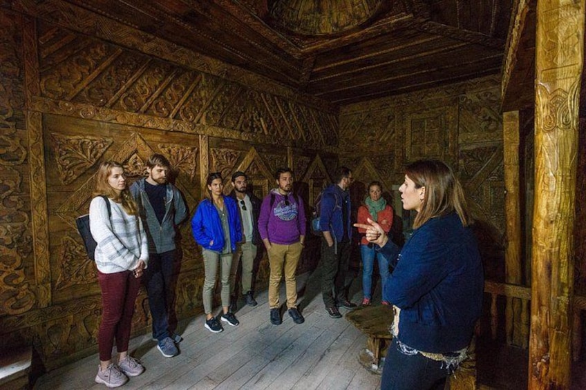 A group of people in a wooden room with intricate carvings on the walls and ceiling. 4