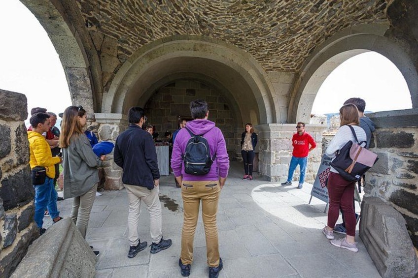 A group of people standing in an ancient stone structure with arches. 2