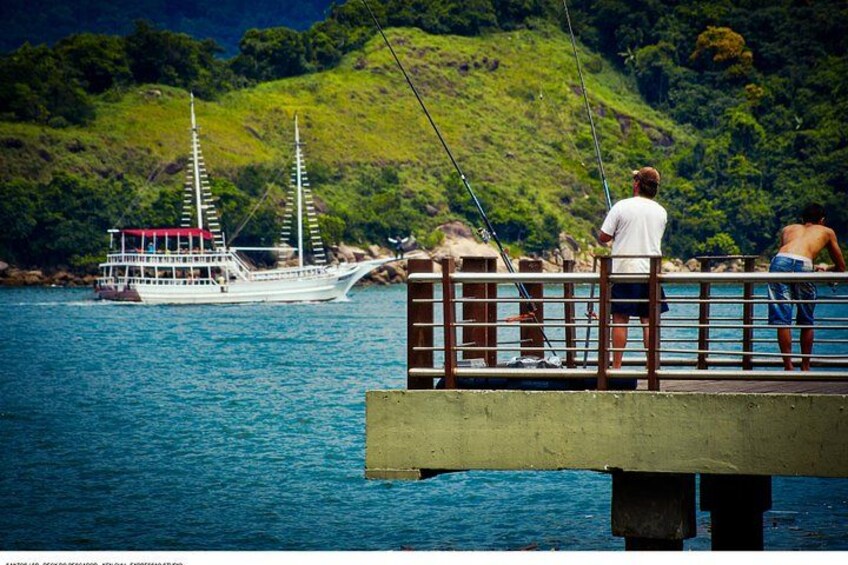 A boat on a body of water, a dock, and a hilly landscape in the background. 2
