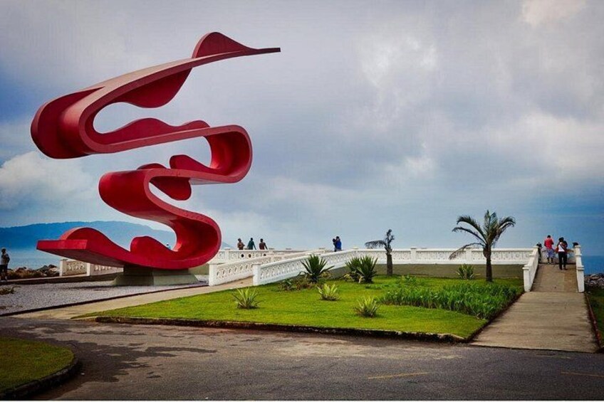 A red spiral sculpture, a white bridge, and a pathway with palm trees. 3