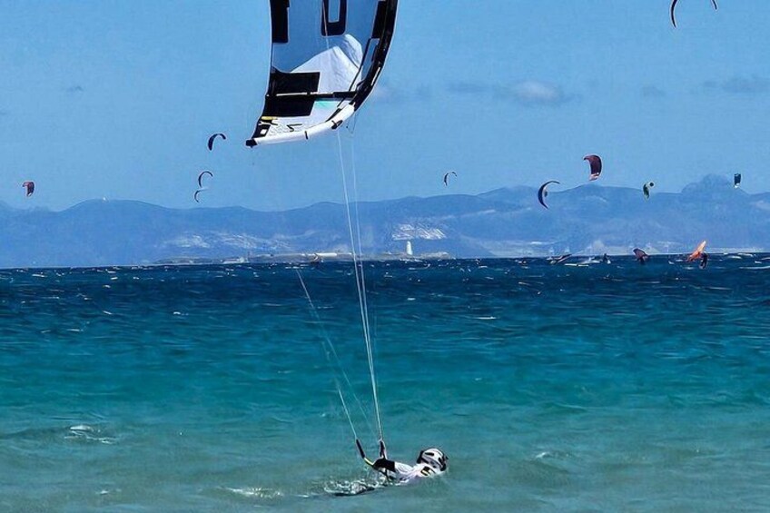Una persona fa parapendio sull'acqua turchese, con montagne sullo sfondo. 3