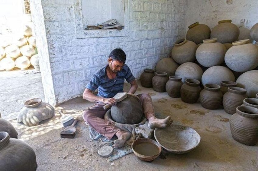 A person working with pottery in a workshop with various clay pots and tools. 2