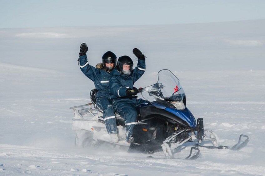 Zwei Personen auf einem Schneemobil in verschneiter Landschaft. 2
