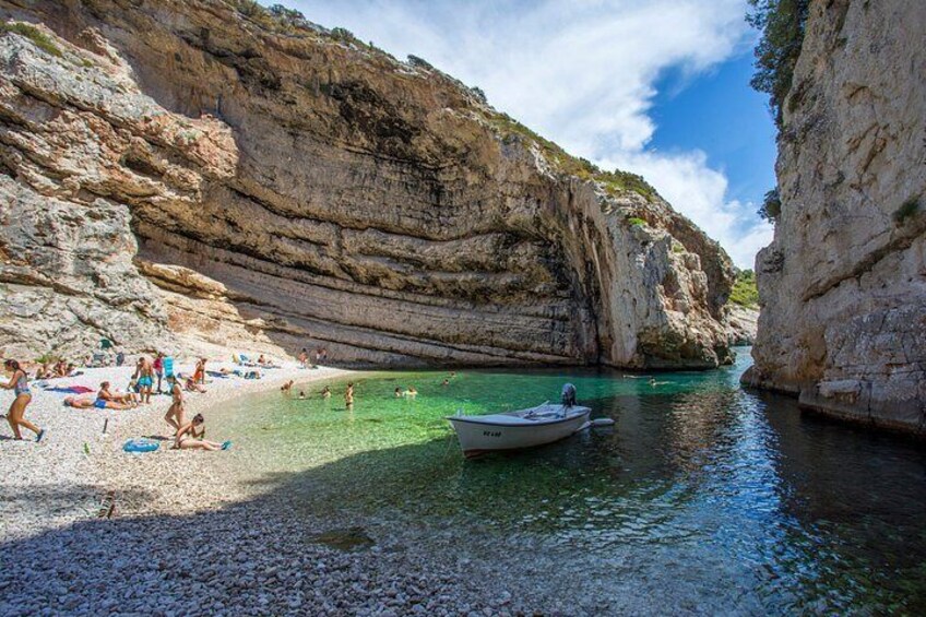 Une plage côtière bordée d’une eau turquoise et limpide, de falaises rocheuses et d’un petit bateau ancré près du rivage. 2