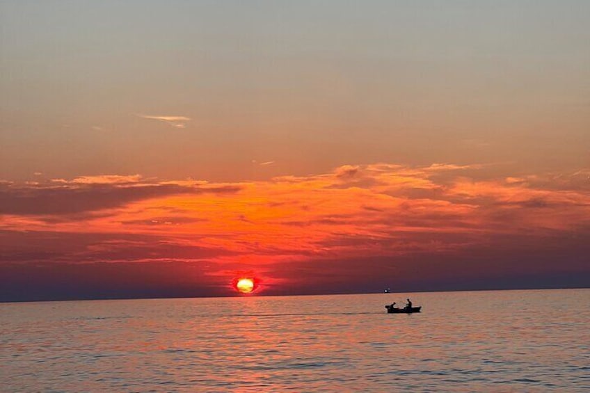 Un atardecer sobre un mar tranquilo con un barco a lo lejos. 3