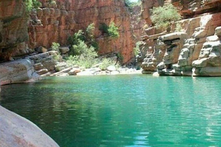 A clear blue pool surrounded by rocky cliffs. 5