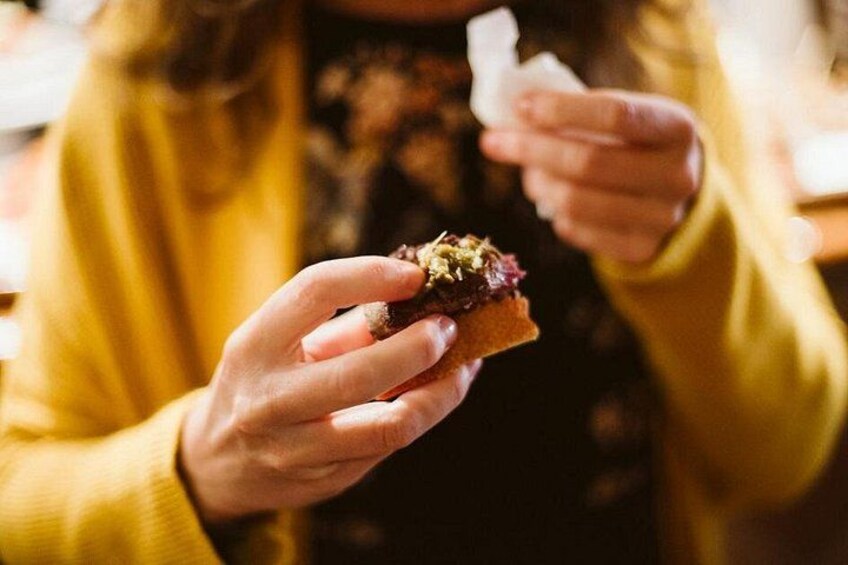 A person holding a sandwich with a dark filling and a piece of bread. 5
