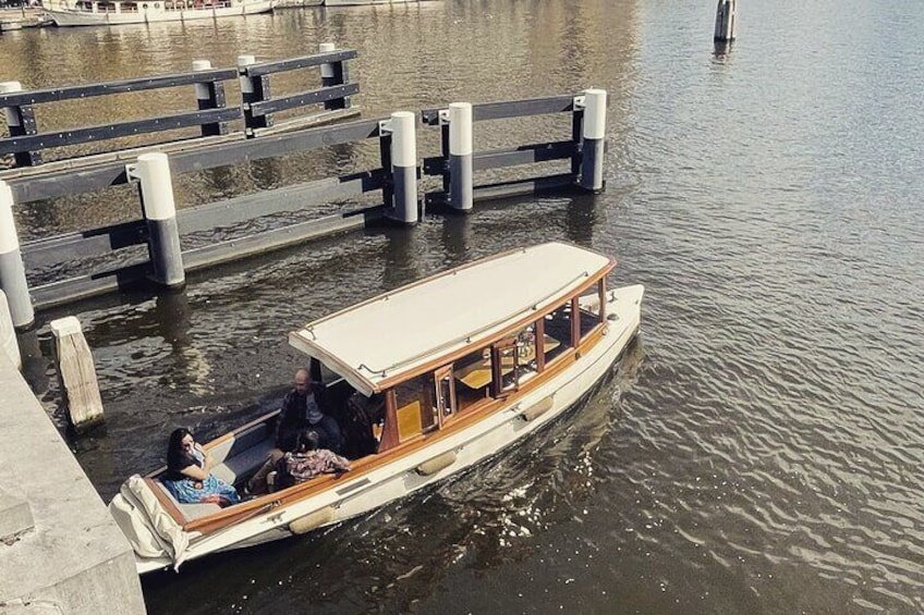 A narrowboat docked at a pier with a wooden deck and passengers on board. 4