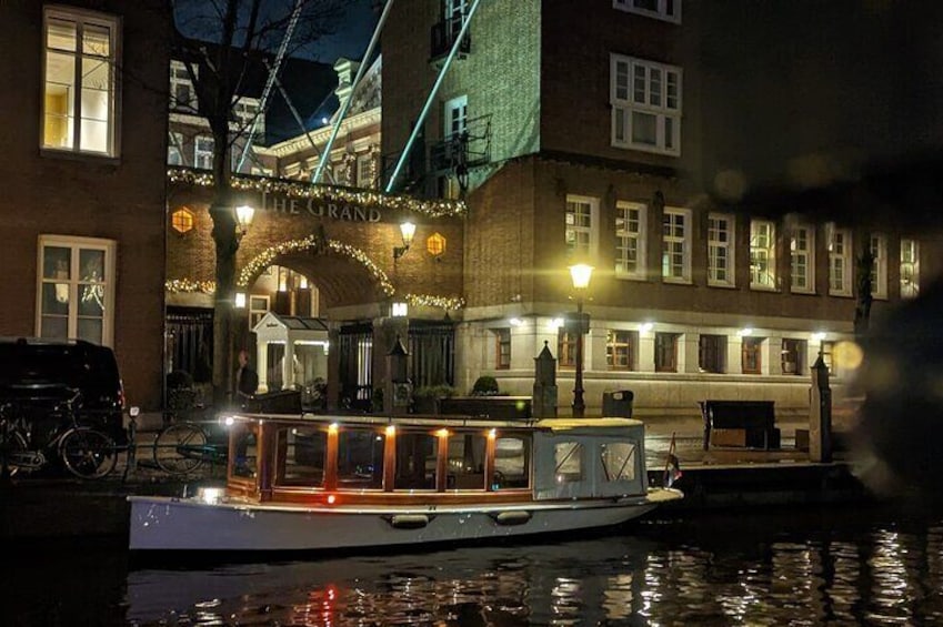 A boat docked at a waterfront with illuminated buildings and a bridge in the background. 5