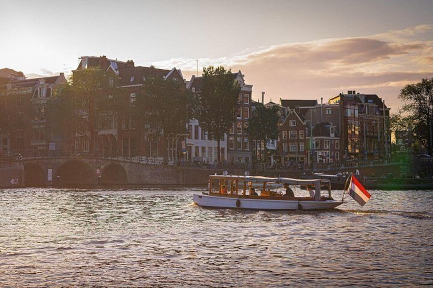 A boat with passengers on a river, a bridge, and buildings along the riverbank. 2