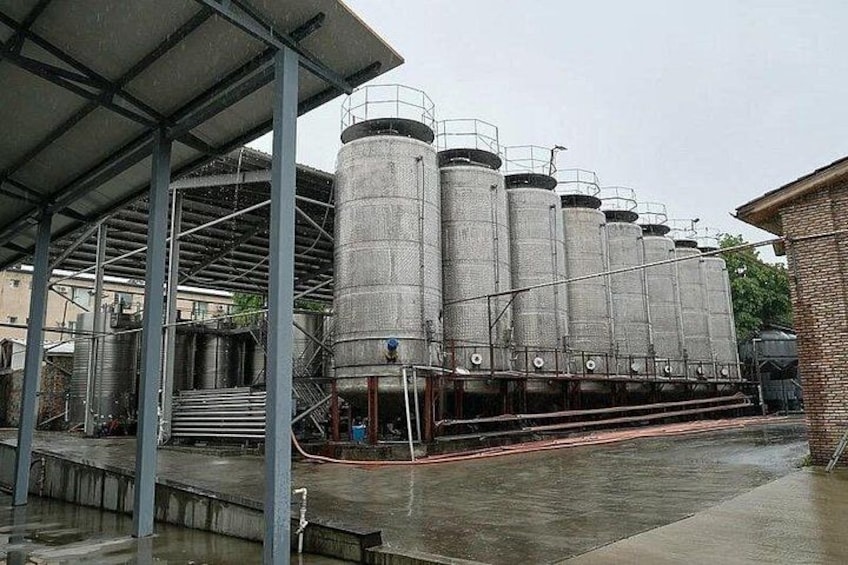 Store industrisiloer, en overdækket gangbro og en murstensbygning. 2
