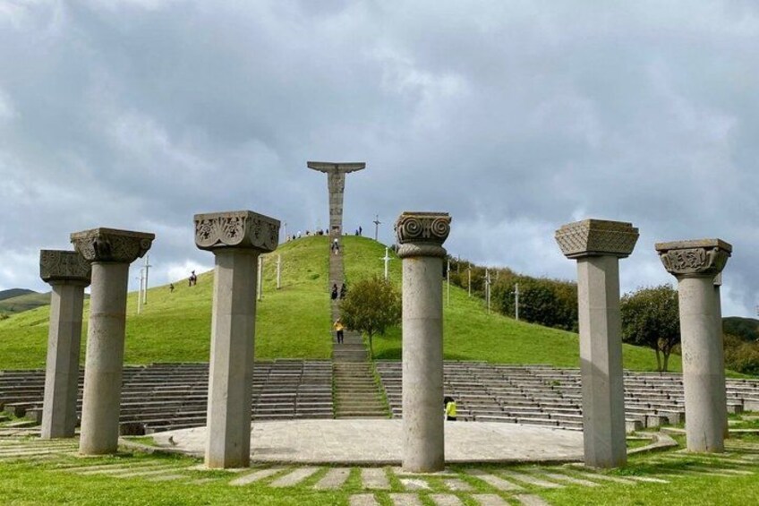 Una serie de columnas de piedra y un monumento central en una colina cubierta de césped. 5
