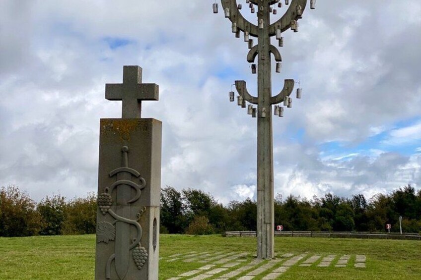 Dos monumentos de piedra con cruces y adornos de vid en un campo cubierto de hierba. 4