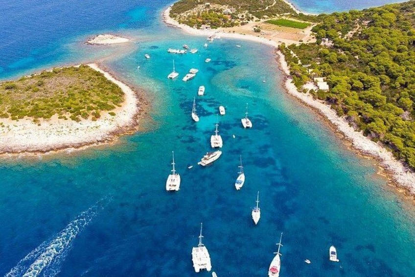 Une zone côtière aux eaux turquoise et limpides, où sont amarrés plusieurs bateaux, et une petite île couverte d’une végétation luxuriante. 5