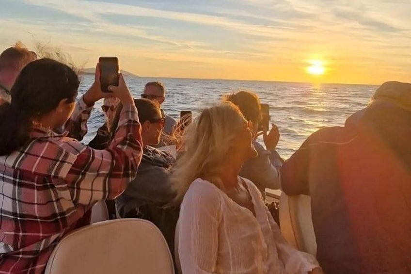 Un groupe de personnes à bord d’un bateau au coucher du soleil. 1