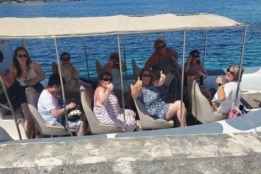 Un groupe de personnes se trouve sur un bateau doté d’un auvent, assises sur des chaises, avec la mer en arrière-plan. 3