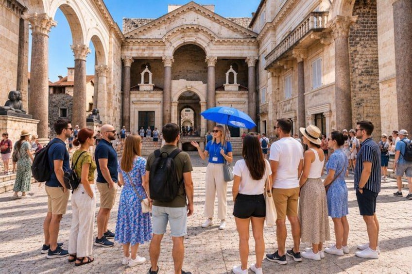 Tourists standing in front of a historic building with columns and arches. 1