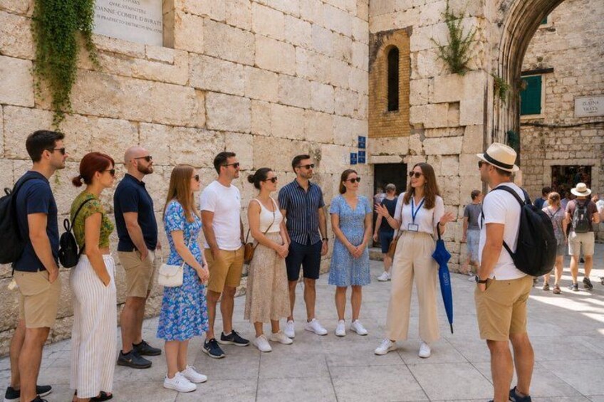 A group of people standing in a stone-paved area with historical architecture in the background. 3