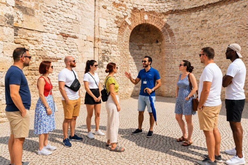 Un gruppo di persone in piedi davanti a un edificio storico in pietra con un portale ad arco. 2