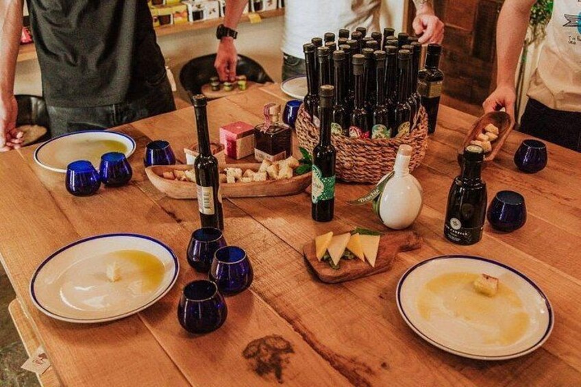 Un tavolo di legno con bottiglie di vino, formaggio e bicchieri blu. 5