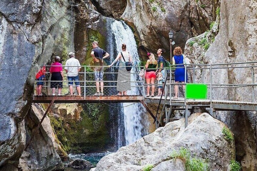 Un groupe de personnes se tient sur un pont surplombant une cascade. 5