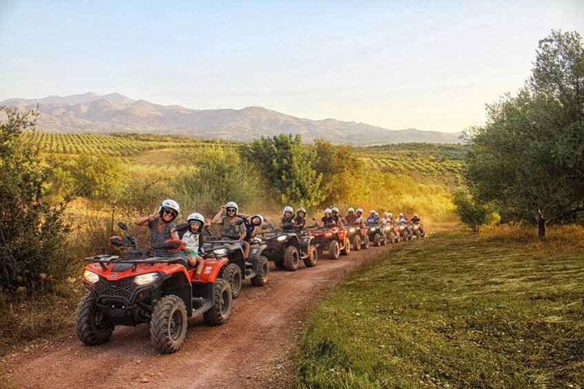 Un grupo de personas en cuatrimotos por un camino de tierra en una zona rural, con campos y montañas al fondo. 3