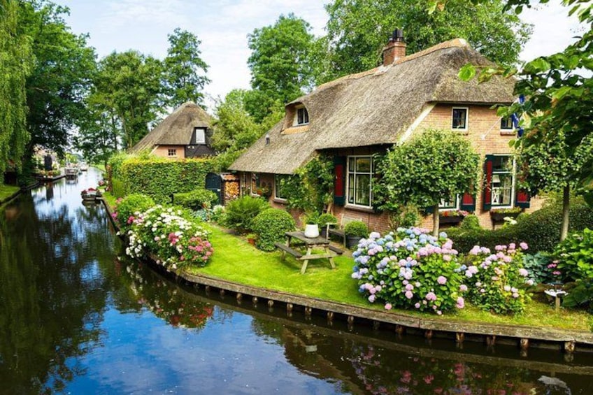 A canal with houses on one side and lush greenery on the other. 1