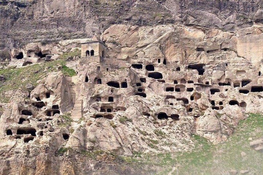 A rocky landscape with numerous cave dwellings carved into the cliffs. 1