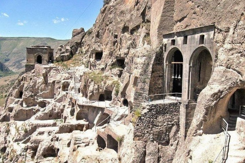 Ancient rock-cut architecture with multiple caves and structures carved into the hillside. 3