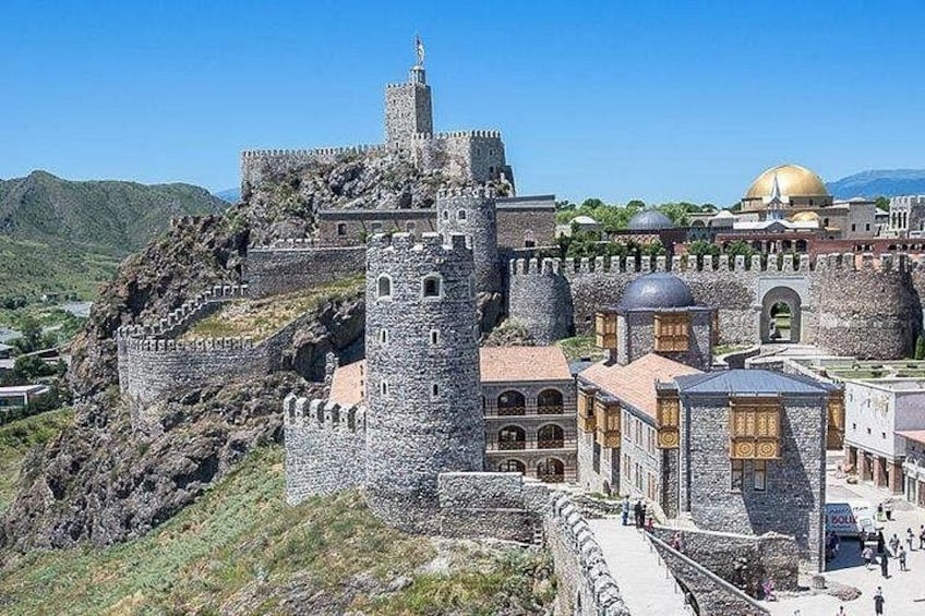 A historic stone fortress with a prominent tower, a golden dome, and a surrounding wall. 4