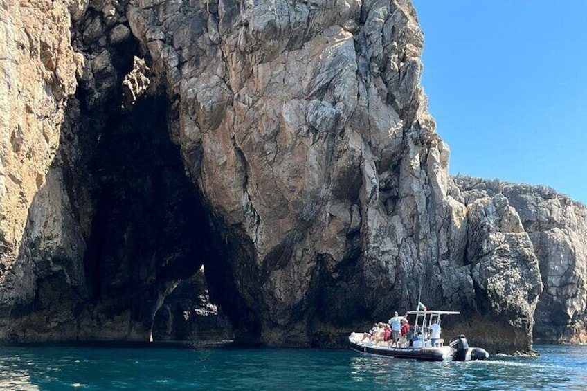 A boat near a rocky cave entrance with clear blue water. 4