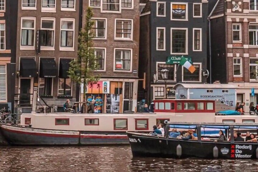 Un canal con barcos, un bote rojo con gente y edificios con tiendas. 2