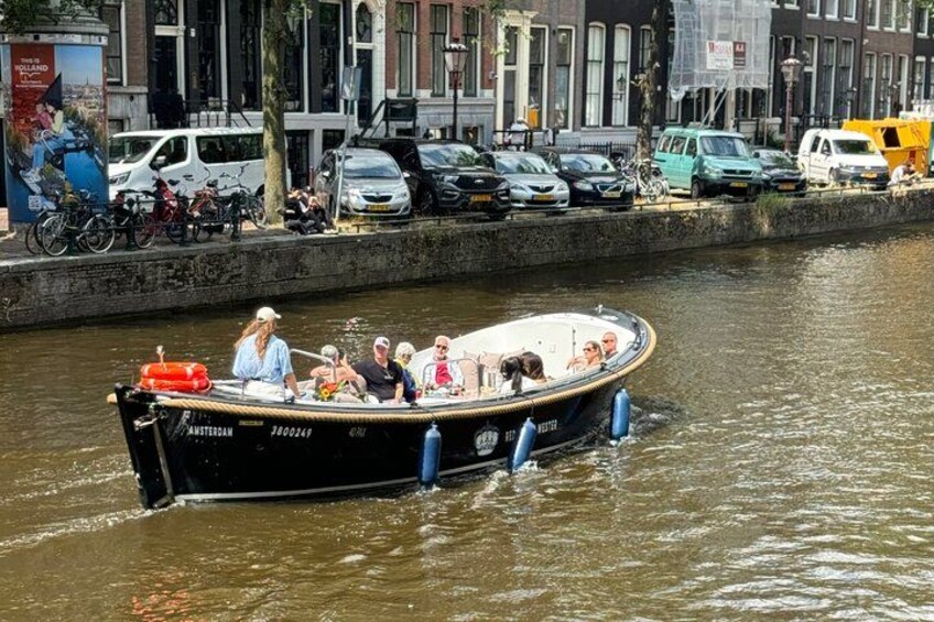 Un bateau avec des personnes à bord, un canal et des voitures garées le long du quai. 3