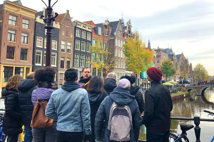 Een groep mensen staat langs een gracht in een stad met historische gebouwen. 4