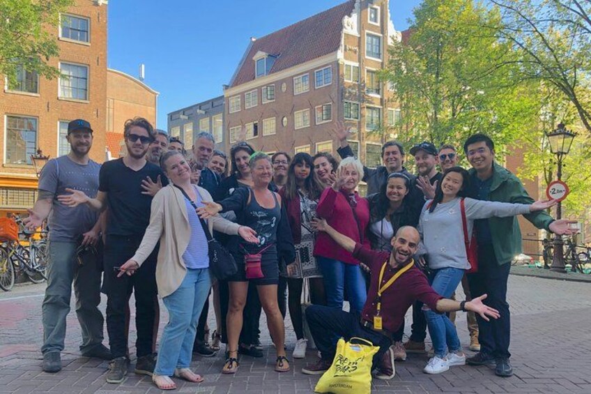 Een groep mensen die poseert voor een foto op een straat in de stad, met gebouwen en bomen op de achtergrond. 5