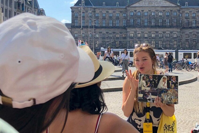 Une personne tenant un album photo contenant de nombreuses images, avec un grand bâtiment historique en arrière-plan et une foule de personnes. 4
