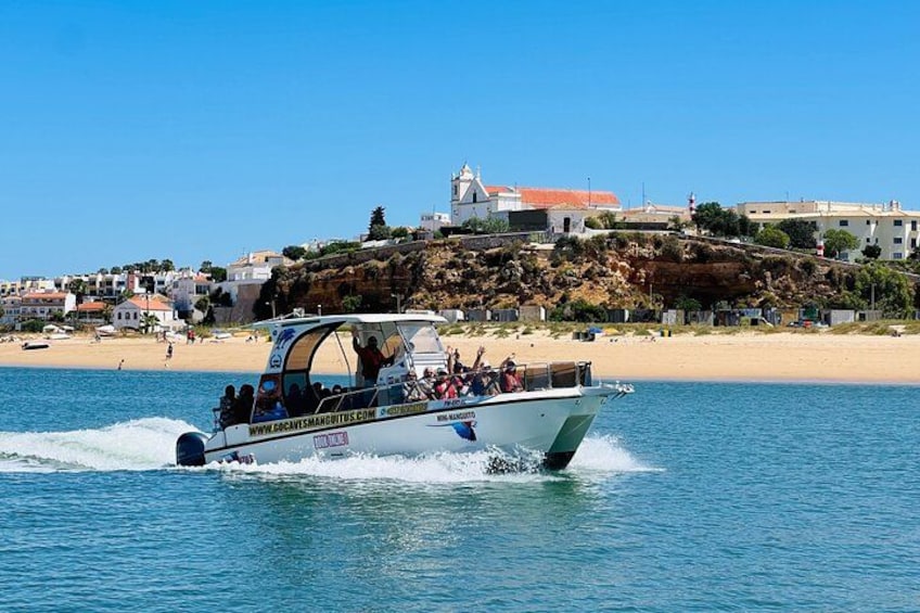 A boat speeding across a calm sea with a coastal town in the background. 3