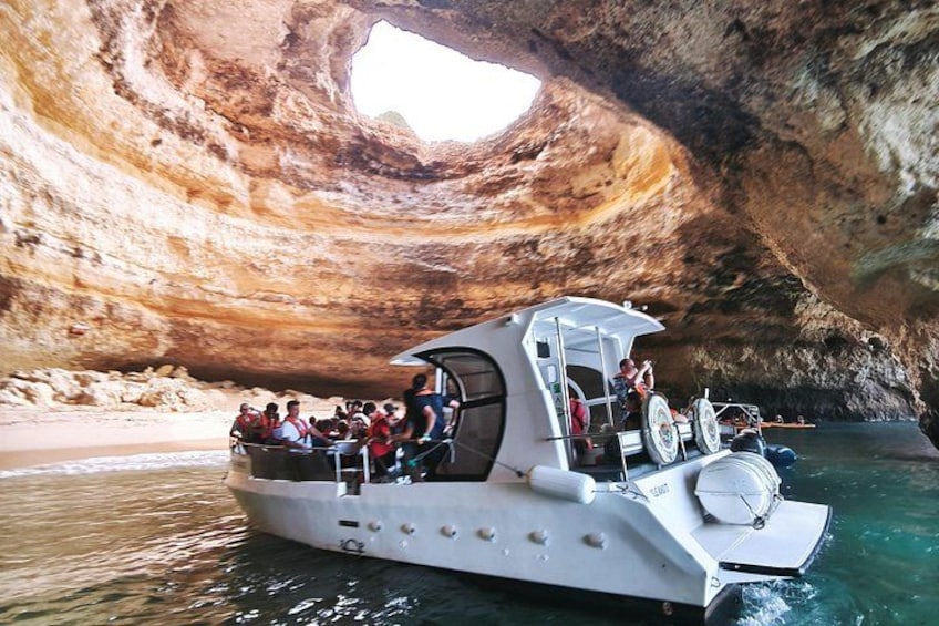 A boat with passengers exploring a large natural rock formation. 3