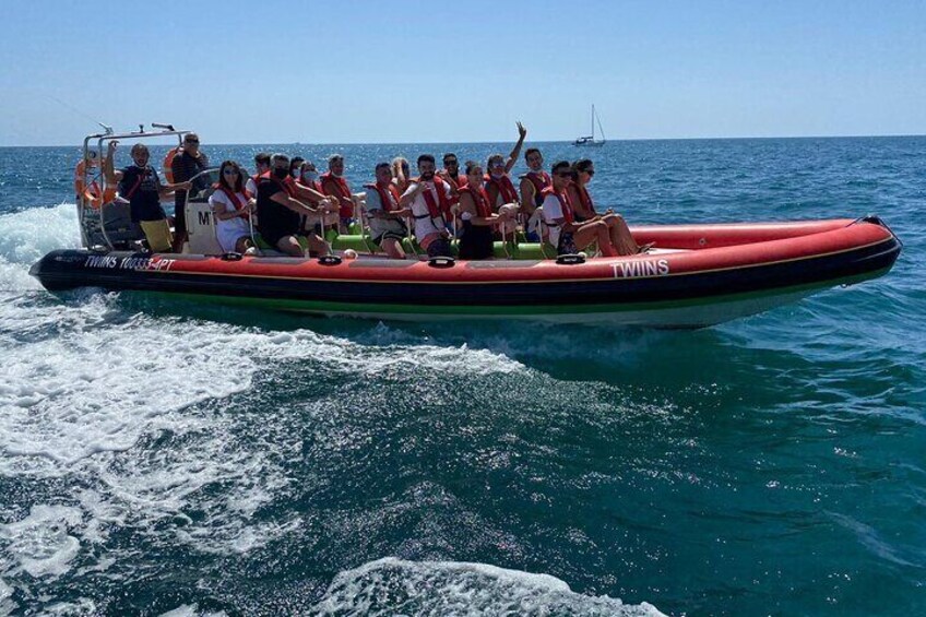 Eine Gruppe von Menschen in einem roten Schlauchboot mit der Aufschrift 'TWINS', das auf dem Wasser treibt. 2
