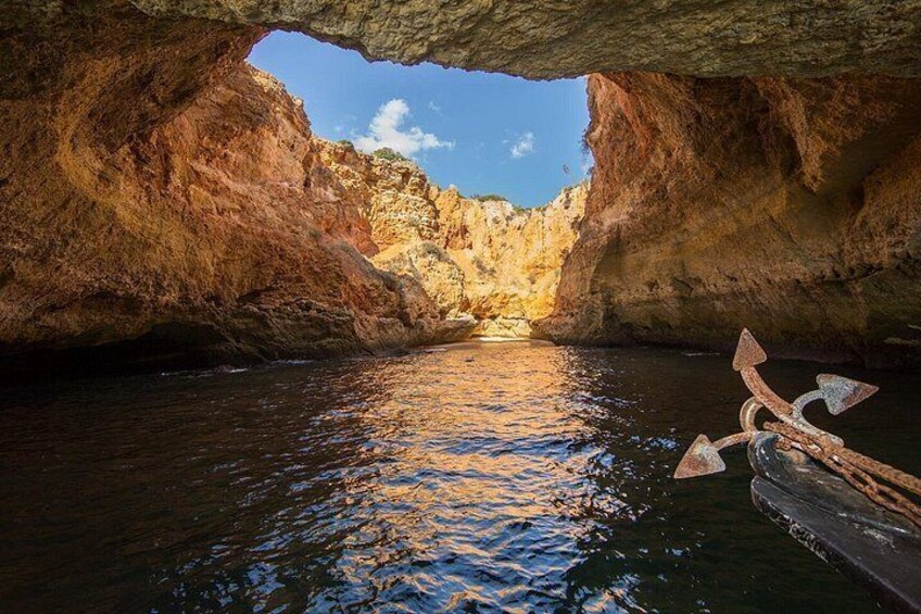A cave opening with water inside, a wooden structure, and rocky walls. 1