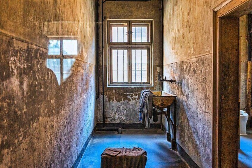 A narrow, dimly lit hallway with a window, a sink, and a bucket. 3