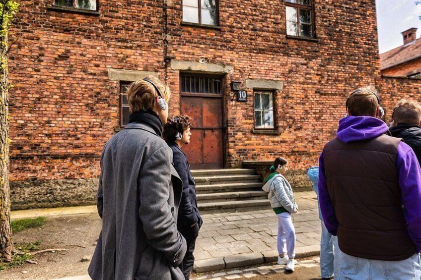 A group of people standing in front of a brick building with a number '10' sign. 5