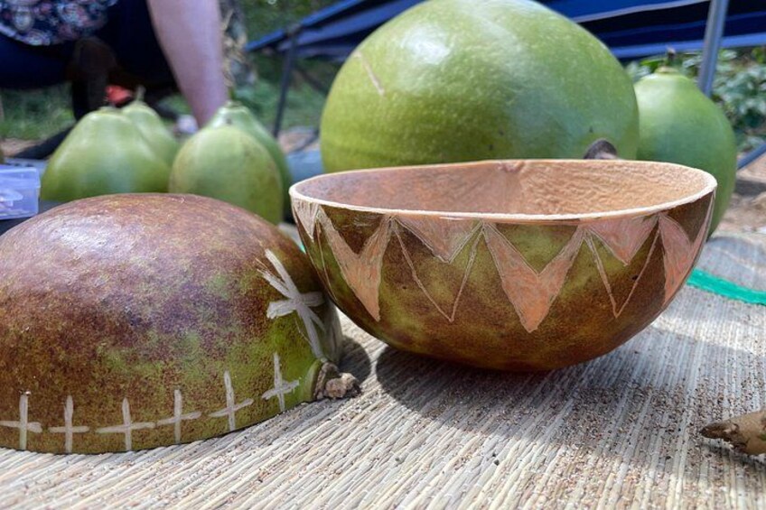 A carved wooden bowl and a green fruit on a table. 4
